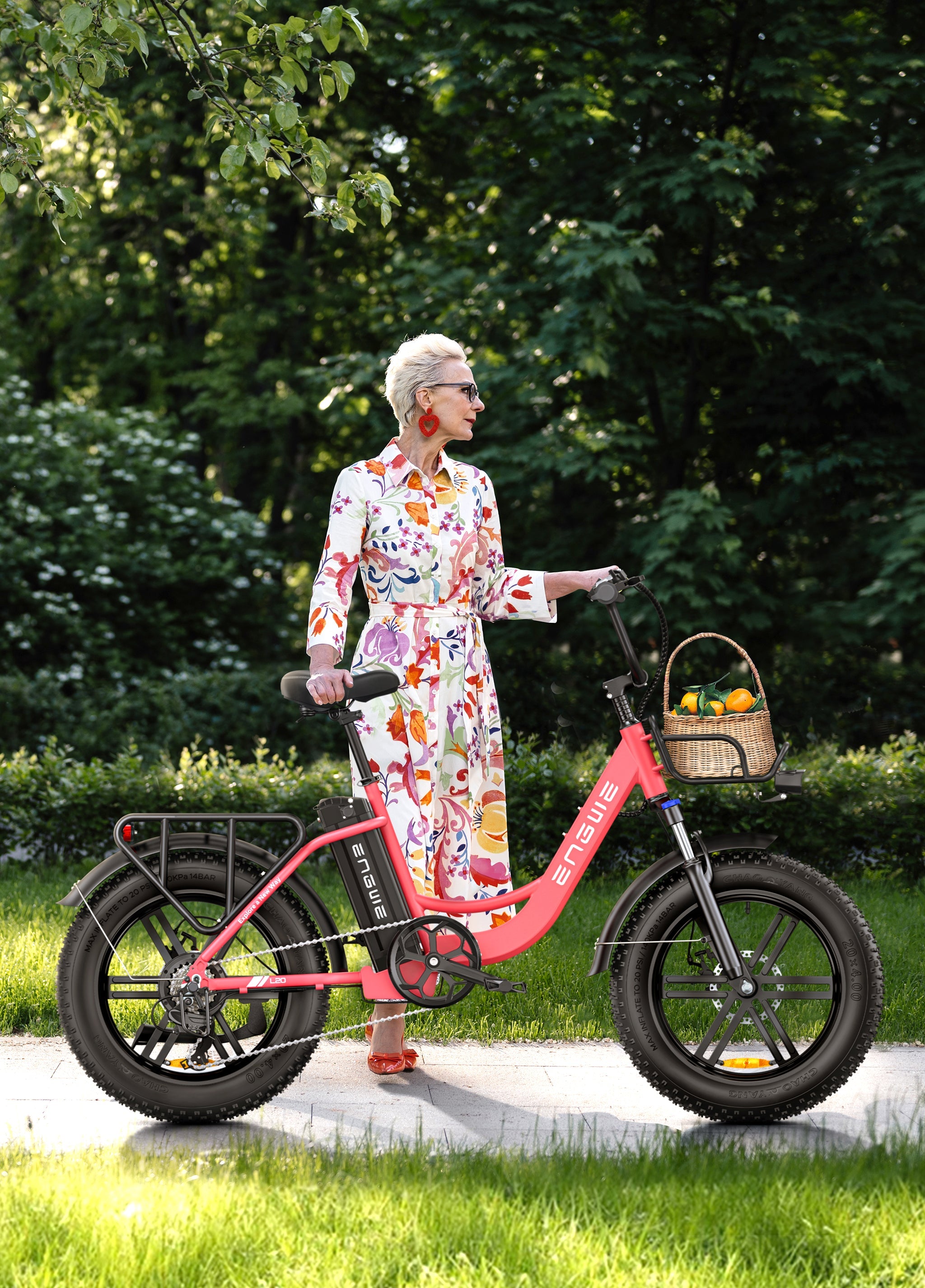 Woman in a floral dress standing beside the Engwe L20 electric bike in a lush green park.