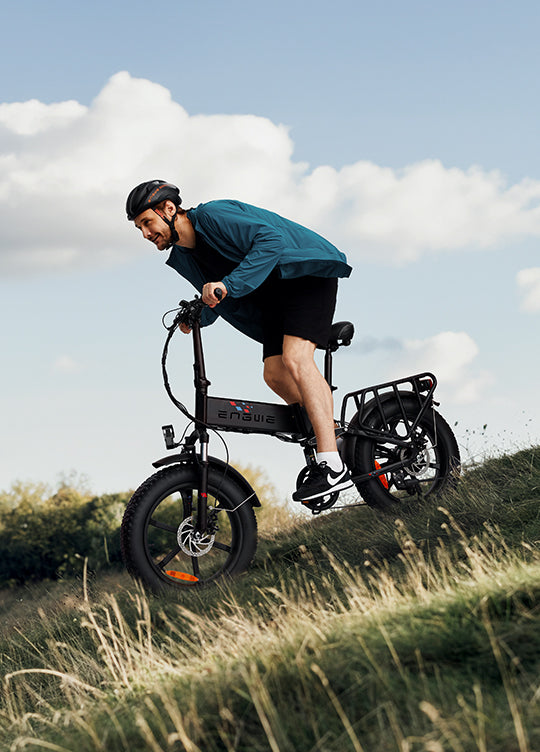 A cyclist riding the ENGWE Engine X e-bike on a hill, showcasing its power and off-road capabilities.